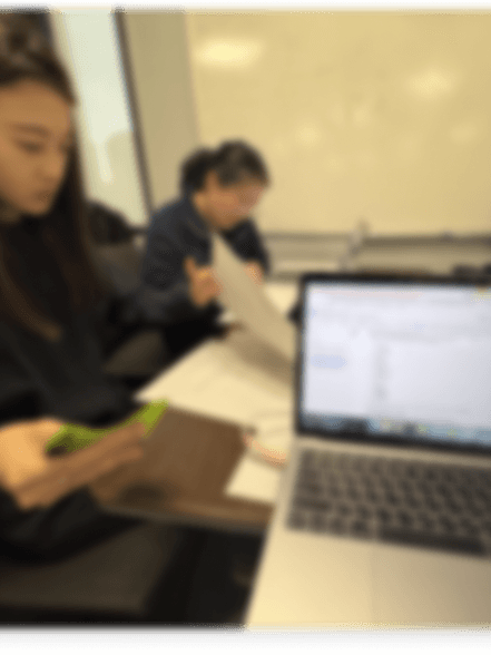 Blurred photograph of a moderated research session with a participant using a phone beside a laptop